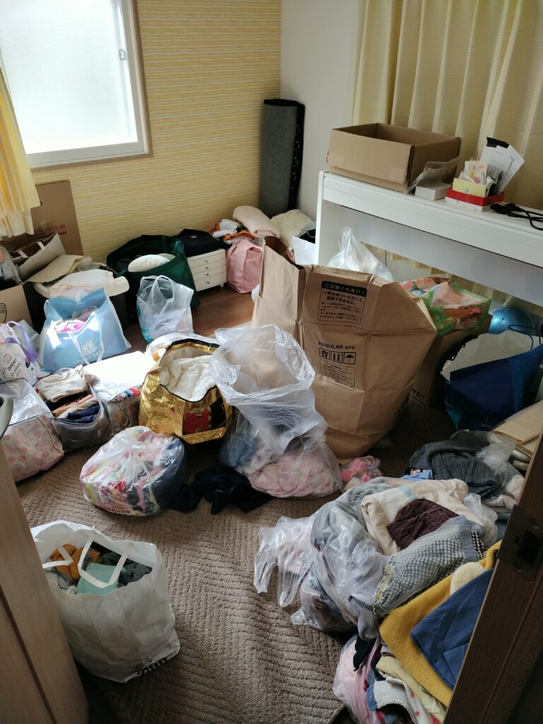 茨木市にお住いのN様。引っ越し後そのままの状態で数年経過。引っ越し後の段ボールや子ども服が積み重なった片づけ前の様子