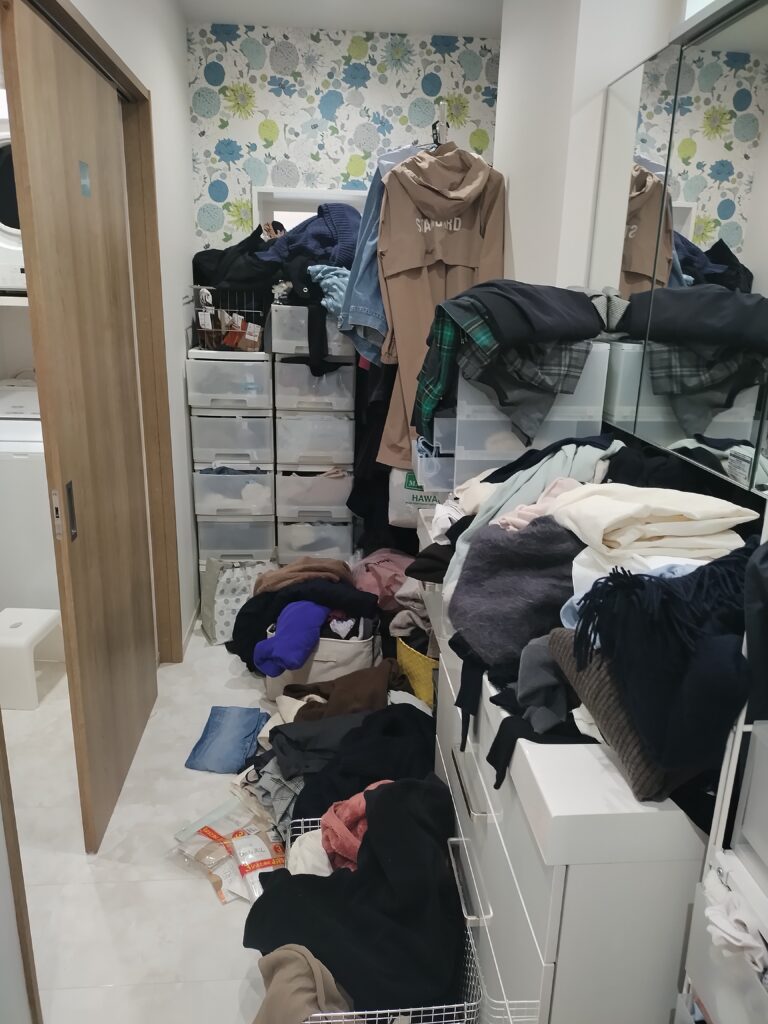 服があふれて床や引き出しの上まで積み上がってしまっていた片づけ前の洗面所
