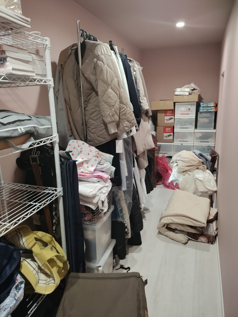 ラックには物が収納されていないが、直置きになり、歩きづらいウォークインクローゼット。片付け前。
